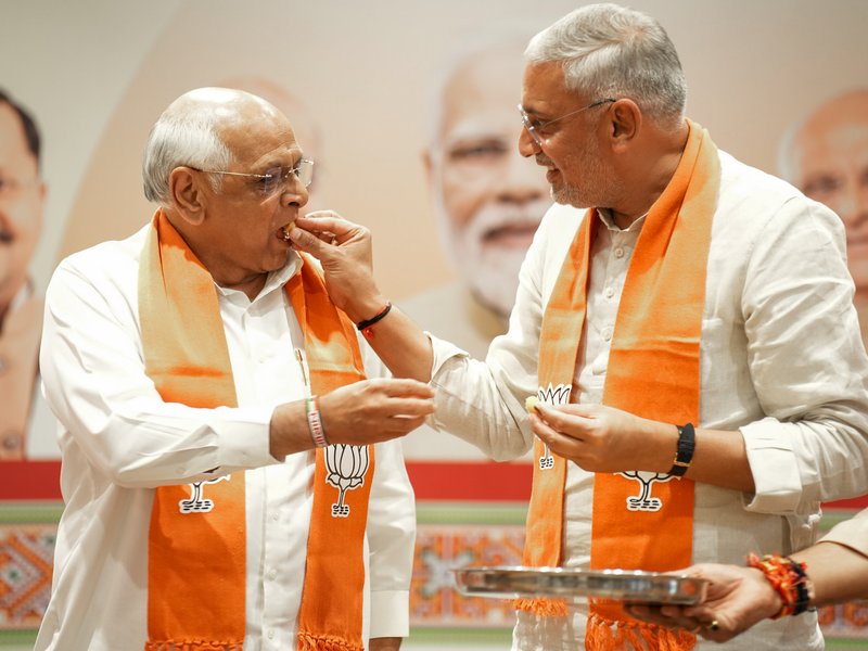 Gandhinagar: Gujarat Chief Minister Bhupendra Patel and State BJP President Jagdish Vishwakarma offer each other sweets during a press conference following the Bharatiya Janata Party’s victory in local body elections across the state in Gandhinagar on Tuesday, April 28, 2026. (Photo: IANS/X/@BJP4Gujarat)