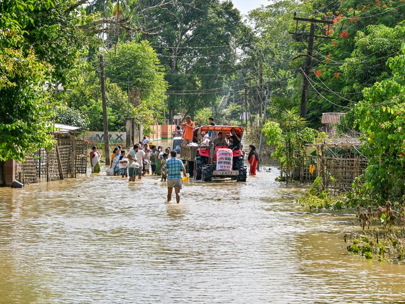Sivasagar: Volunteers distribute relief materials to flood-affected residents using a tractor following heavy monsoon rains in Assam's Sivasagar district on Monday, July 27, 2026. (Photo: IANS)